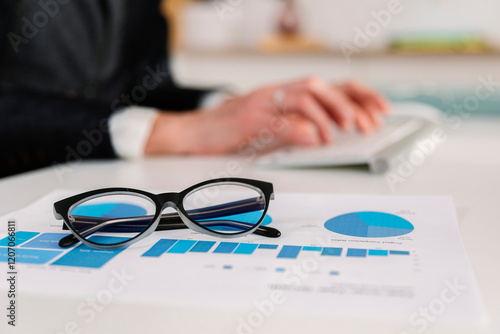 Eyeglasses over bar graph diagram with businesswoman working in background at office photo