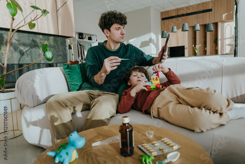 Son playing with toy and father using tablet PC at home photo