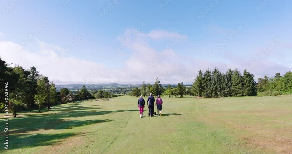 Golf players walking with clubs and talking on golf course, copy space Golf players walking with clubs and talking on golf course, copy space