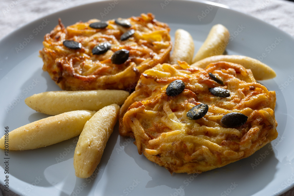 Pumpkin grated roasted patties, rosti or latkes and Fingernudel, finger potato noodle, dumplings decorated with pumpkin seeds Pumpkin grated roasted patties, rosti or latkes and Fingernudel, finger potato noodle, dumplings decorated with pumpkin seeds