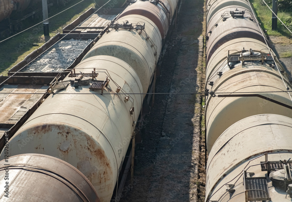 Railway freight cars lined up under clear blue sky at a transportation yard Railway freight cars lined up under clear blue sky at a transportation yard