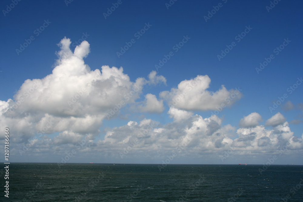 Obraz premium Seascape with white clouds in a blue sky and the North Sea on the coast of The Netherlands