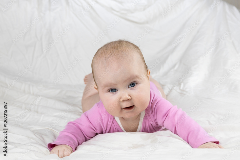 Cute and beautiful 4-month-old baby girl laying on bed and look at the camera. Infant in pink bodysuit on bed against white background. Cute and beautiful 4-month-old baby girl laying on bed and look at the camera. Infant in pink bodysuit on bed against white background.