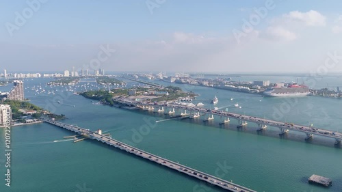 Wallpaper Mural Aerial drone view of Miami’s Biscayne Bay with bridges, luxury yachts, cruise ships, and the port, featuring a rooftop foreground under a partly cloudy sky. Torontodigital.ca
