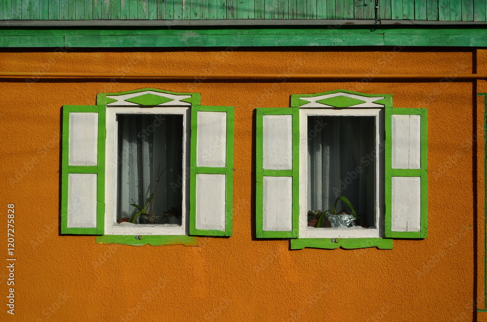 two windows with shutters on the orange wall of the house two windows with shutters on the orange wall of the house