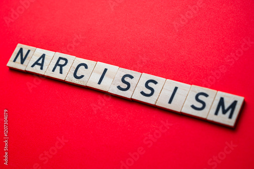 Word Narcissism, written with wooden alphabet blocks, on red surface. photo