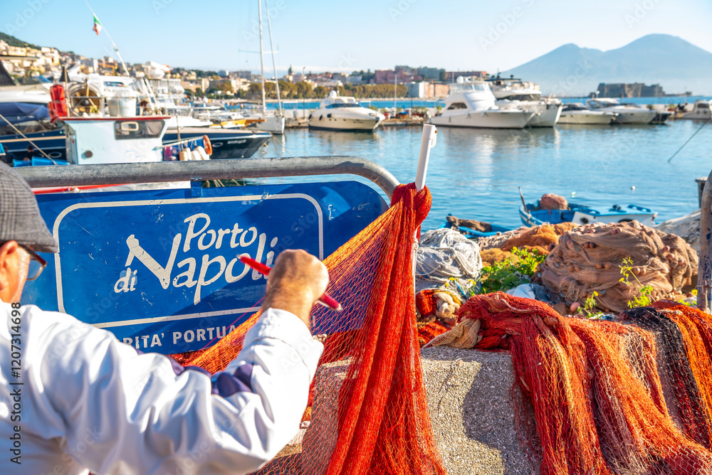 Boat dock in Naples. An old fisherman weaves a fishing net. A sign in Italian that says