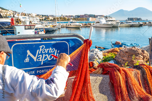 Obraz na płótnie Boat dock in Naples. An old fisherman weaves a fishing net. A sign in Italian that says