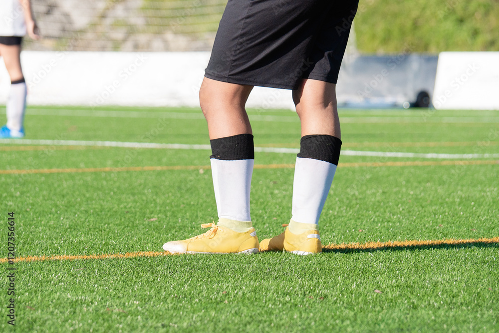 Soccer Player Standing on Green Soccer Field with Yellow Cleats Soccer Player Standing on Green Soccer Field with Yellow Cleats