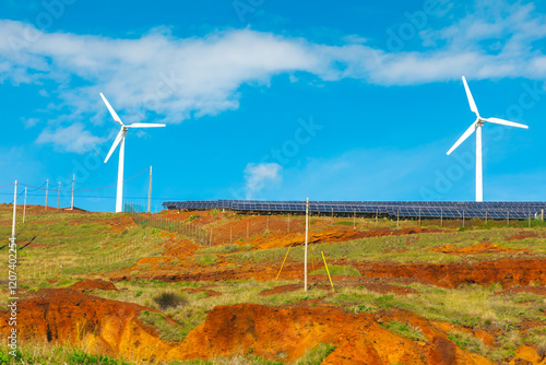 Obraz na płótnie Landscape with wind turbines and a solar panel array on a grassy, hilly terrain under blue sky. Renewable energy sources, highlighting the use of wind and solar power for sustainable energy production w salonie