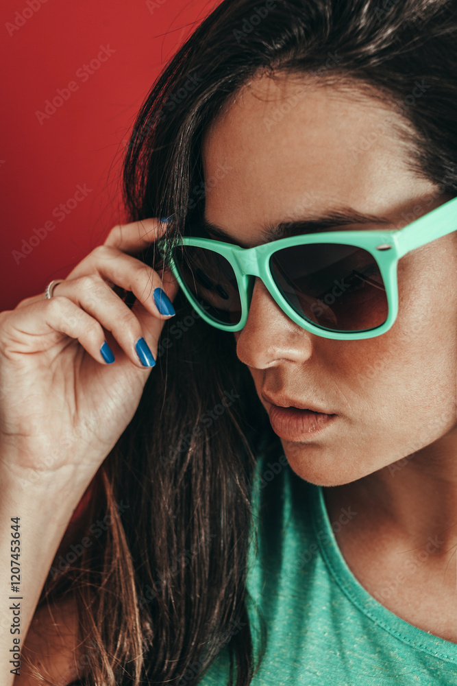 Woman in sunglasses posing stylishly against red backdrop Woman in sunglasses posing stylishly against red backdrop