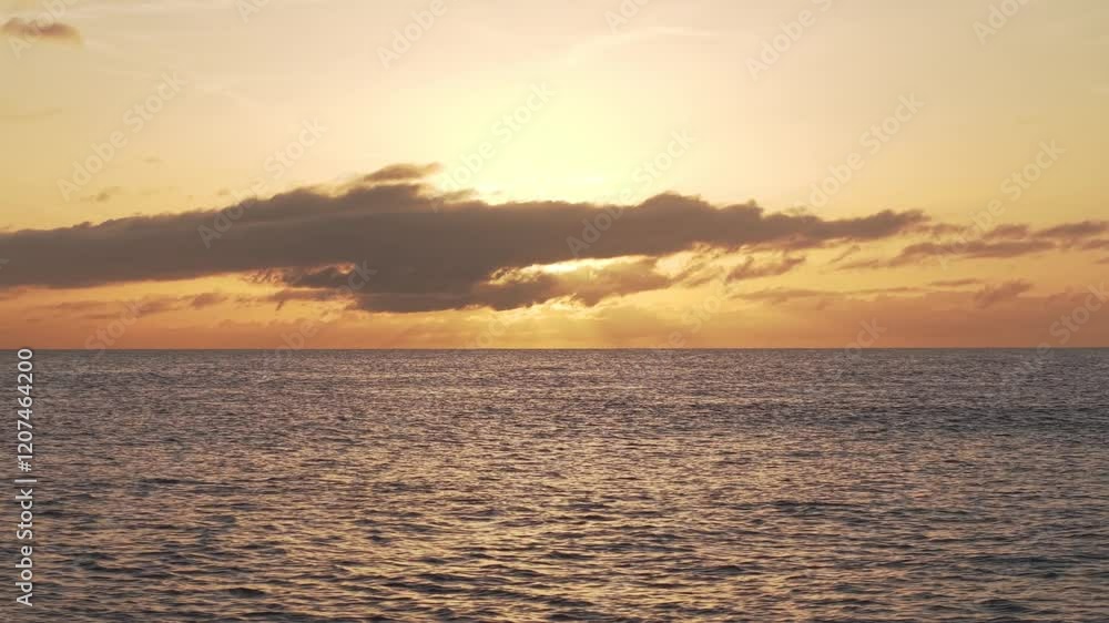 Warm golden sunset casting dramatic light over Atlantic Ocean coastline near Santa Cruz de La Palma, Canary Islands, soft clouds diffusing dramatic sky panorama