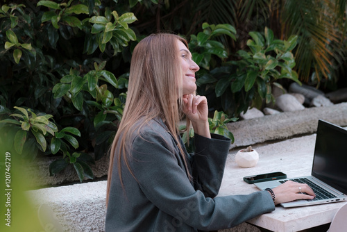 business style dressed long hair young adult woman working on lapton in the garden, green environment, distance dream work, e learning, distance relations or running business concept photo