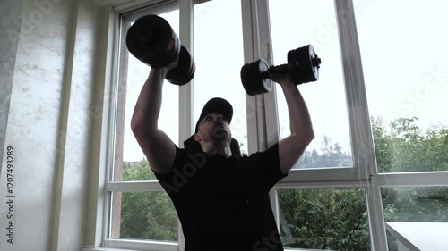 Pumping shoulders with dumbbells in training. Young athlete athlete trains shoulders. Slow motion