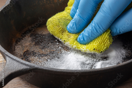 Bild auf Leinwand Person cleaning a rusty old cast iron fying pan using bicarbonate of soda and a scouring pad