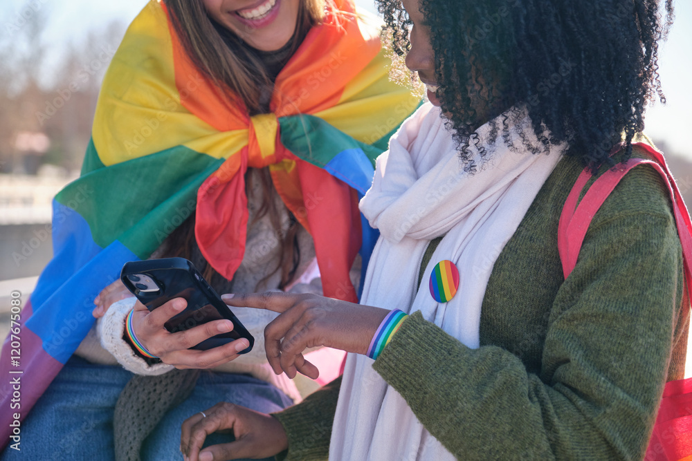 Two friends showing support for lgbt community using rainbow flag and bracelet, sharing content on a social network with a smartphone
