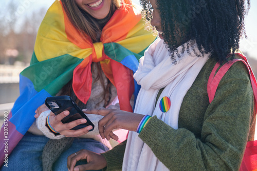 Obraz na płótnie Two friends showing support for lgbt community using rainbow flag and bracelet, sharing content on a social network with a smartphone w salonie
