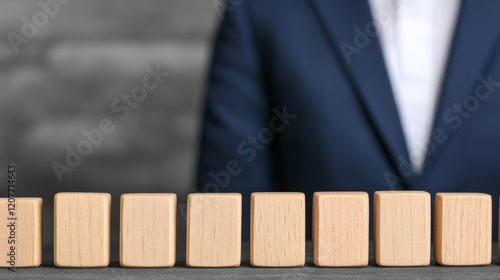 Strategic Alignment: A businessman stands behind a row of aligned wooden blocks, symbolizing concepts of planning, strategy, and business development.   photo