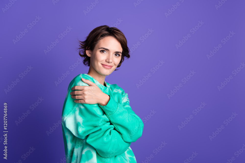 Photo portrait of attractive young woman hugging self dressed stylish green clothes isolated on violet color background Photo portrait of attractive young woman hugging self dressed stylish green clothes isolated on violet color background