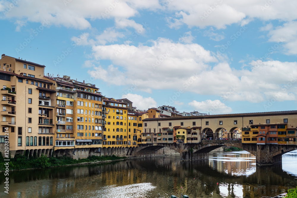 Obraz premium Historic Bridge and Colorful Riverside Buildings Reflected in Calm Water