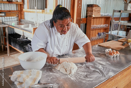 Woman rolling dough on kitchen counter at restaurant photo