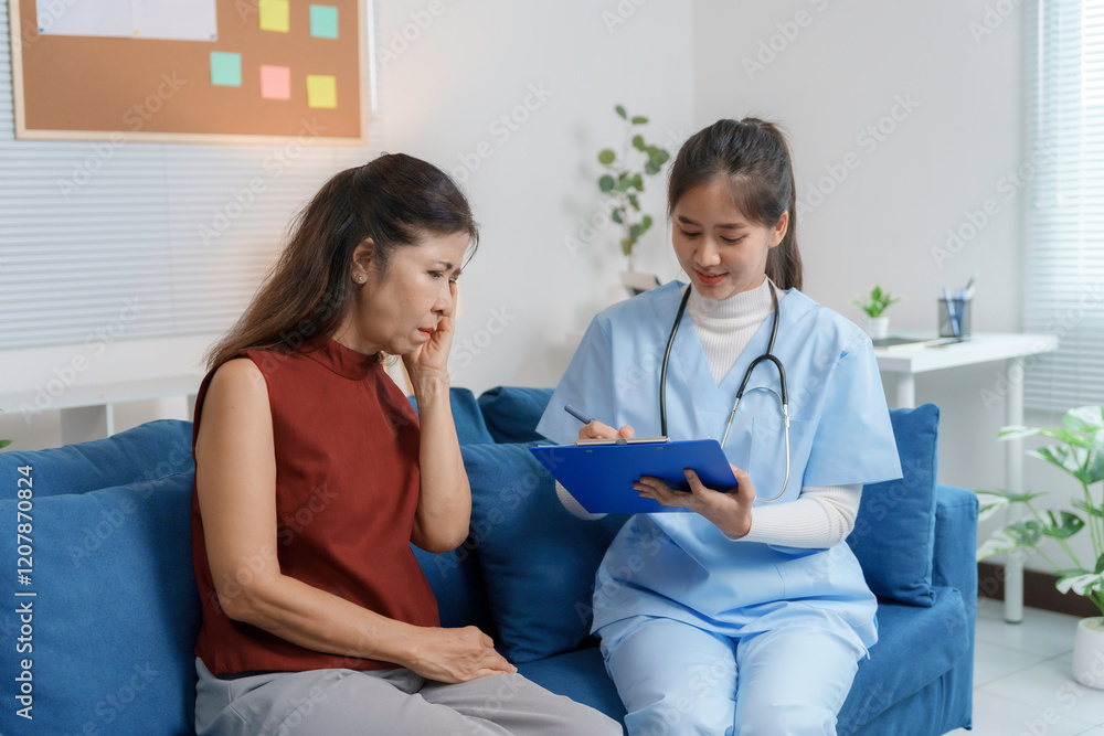 Fototapeta premium Young female doctor writing on clipboard while visiting and examining senior woman at home