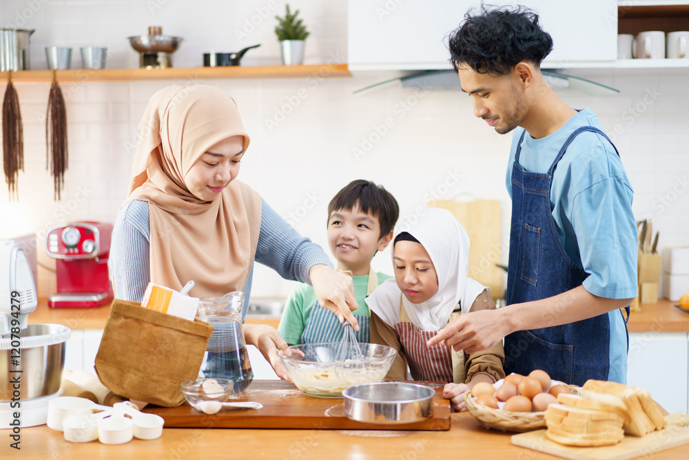 Happy Asian muslim family consisting father, mother, son, and daughter are cooking together in the kitchen. Happy Asian muslim family consisting father, mother, son, and daughter are cooking together in the kitchen.