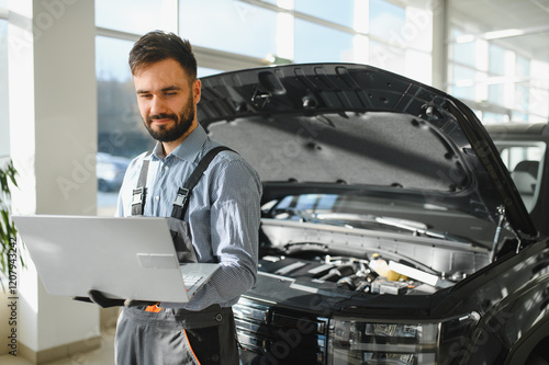 Automotive mechanic running diagnostics software on computer. Mechanic doing vehicle diagnostic test in auto service garage photo