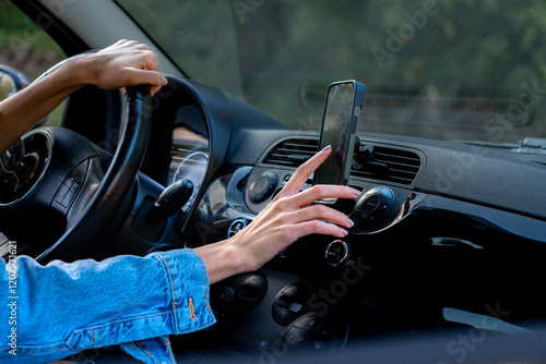 One hand on the wheel, the other reaching for the phone mounted on the support to check directions photo