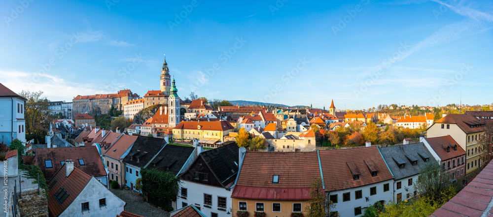 Naklejka premium Panoramic view of Cesky Krumlov, featuring the historic castle tower and the church of St. John of Nepomuk. The medieval town's charm is beautifully captured on a sunny day