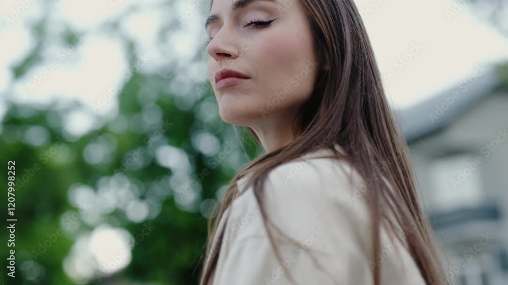 Confident young woman with long brown hair, standing outside on a spring day, looking determined. Serene Young Woman Outdoors with Green Foliage in Background Confident young woman with long brown hair, standing outside on a spring day, looking determined. Serene Young Woman Outdoors with Green Foliage in Background