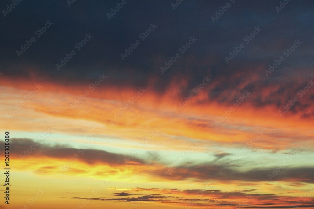 Obraz premium A sunset sky with vibrant hues of orange, pink and purple. The clouds create a dramatic and colorful display. Concept of tranquility of nature. Gradient of colors from deep purple to vibrant orange