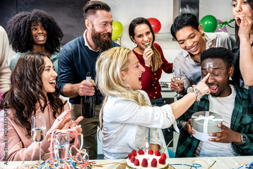 Group of happy people celebrating diverse birthday among friends smiling while having a party - Girl smearing cake on boy's face - Celebration, anniversary and bday concept with friends make a wish