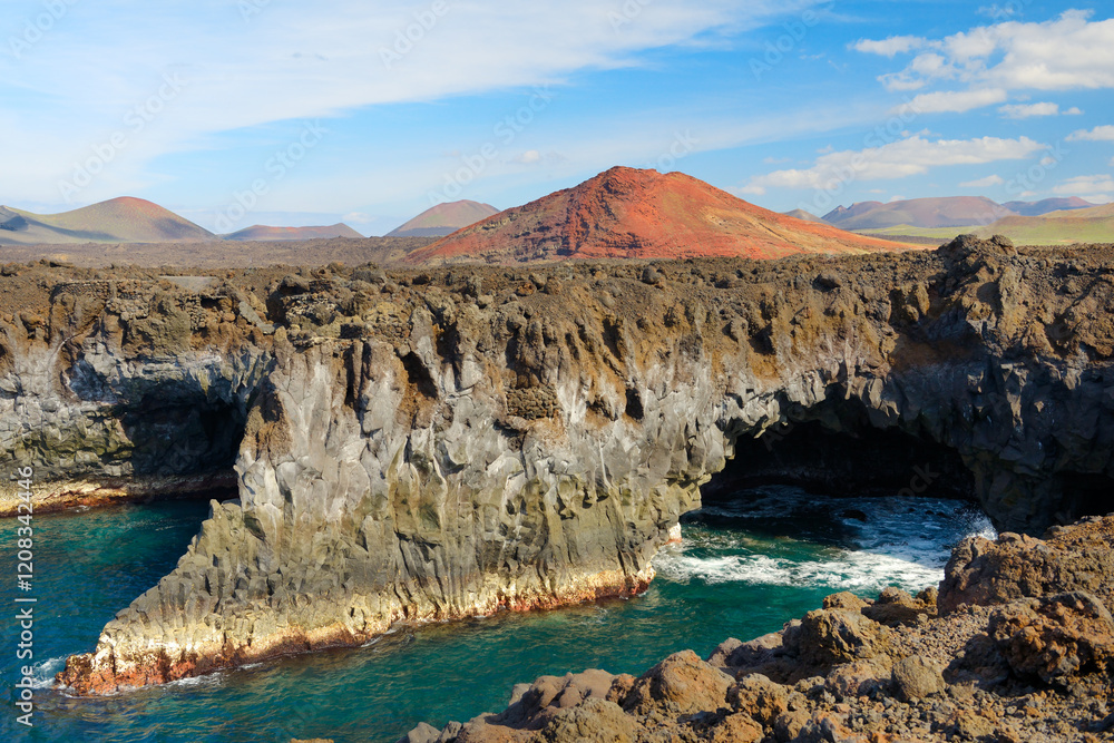 Lanzarote, Canary Islands. Eroded volcanic sea caves cliffs at Los Hervideros and lava cone landscape of Timanfaya National Park