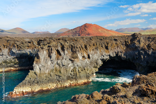 Obraz na płótnie Lanzarote, Canary Islands. Eroded volcanic sea caves cliffs at Los Hervideros and lava cone landscape of Timanfaya National Park w salonie