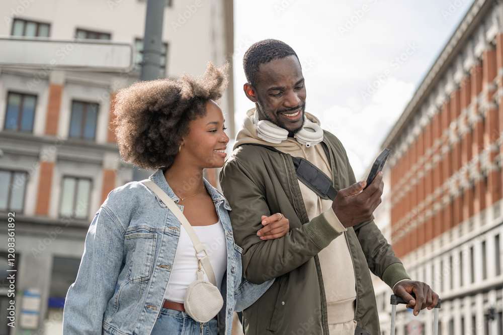 African American traveler couple standing on a street, using smartphones to navigate urban space. Mobile technology and travel concepts. African American traveler couple standing on a street, using smartphones to navigate urban space. Mobile technology and travel concepts.
