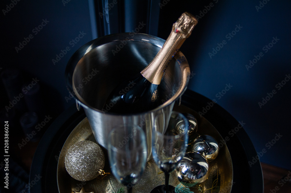 Stylish New Year celebration setup with a champagne bottle in a silver ice bucket, two elegant glasses, gold ornaments, and pine branches on a golden tray, set against a dark, luxurious background Stylish New Year celebration setup with a champagne bottle in a silver ice bucket, two elegant glasses, gold ornaments, and pine branches on a golden tray, set against a dark, luxurious background
