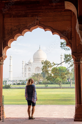 Attractive young woman enjoying the iconic view over the marble white Taj Mahal mausoleum in Agra, Uttar Pradesh, India