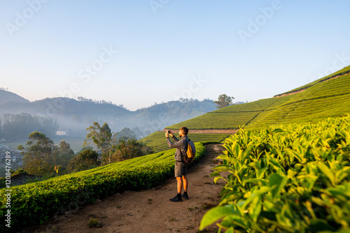 Photography Young man with backpack taking photos of tea plantations in Munnar