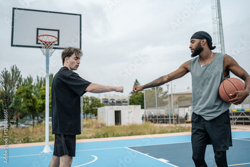 Two basketball players doing fist bump after match on outdoor court photo