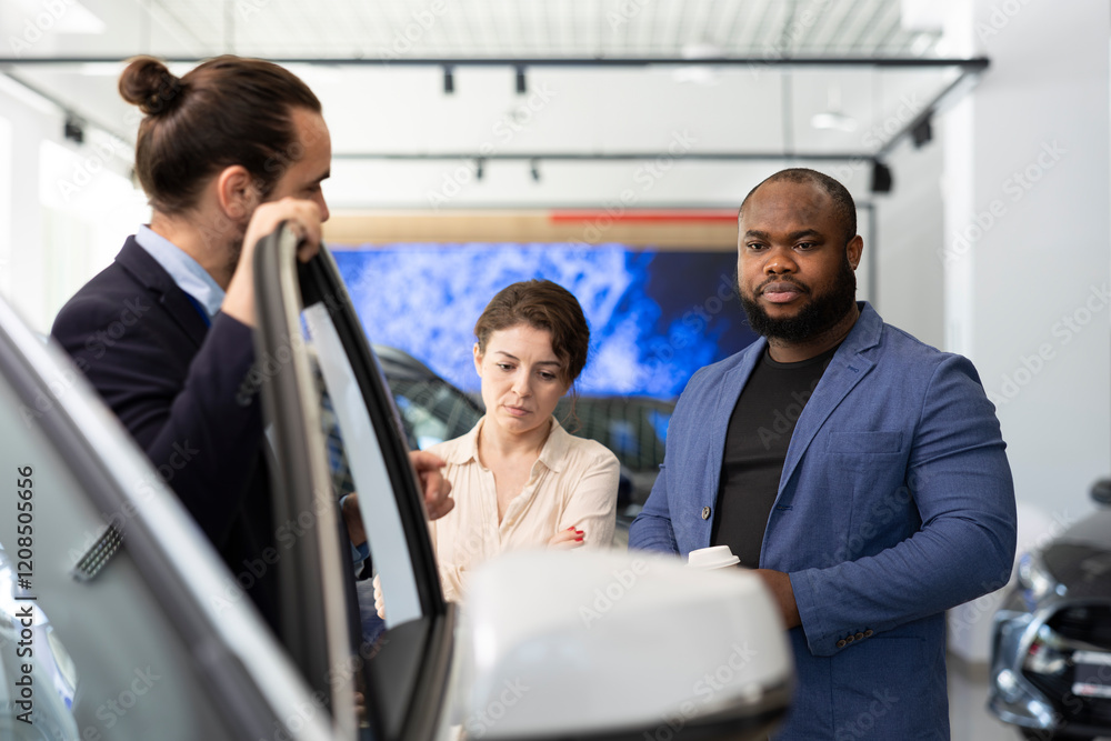Car dealership salesman inviting customers to conduct test drives to demonstrate vehicle capabilities. Showroom employee suggesting clients optional equipment to purchase Car dealership salesman inviting customers to conduct test drives to demonstrate vehicle capabilities. Showroom employee suggesting clients optional equipment to purchase
