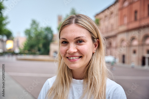 Portrait of Caucasian woman looking at camera and smiling outdoors. Beautiful eastern European girl is happy and cute. She looks positive and attractive and confident laughing standing outside.