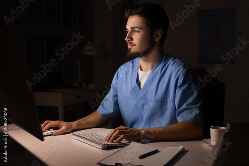 Tableau sur toile Male nurse with computer working evening shift in clinic