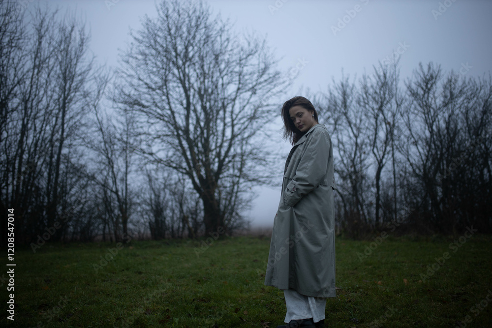 gloomy woman in coat walks alone in foggy field, existential crisis