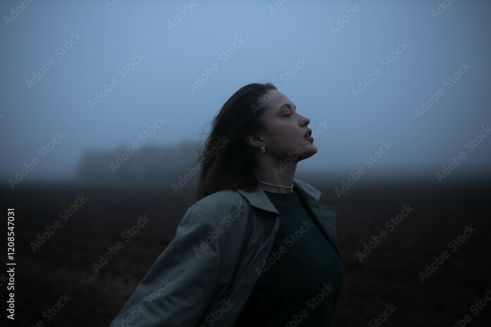 gloomy woman in coat walks alone in foggy field, existential crisis