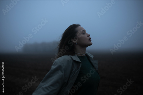 Obraz na płótnie gloomy woman in coat walks alone in foggy field, existential crisis w salonie