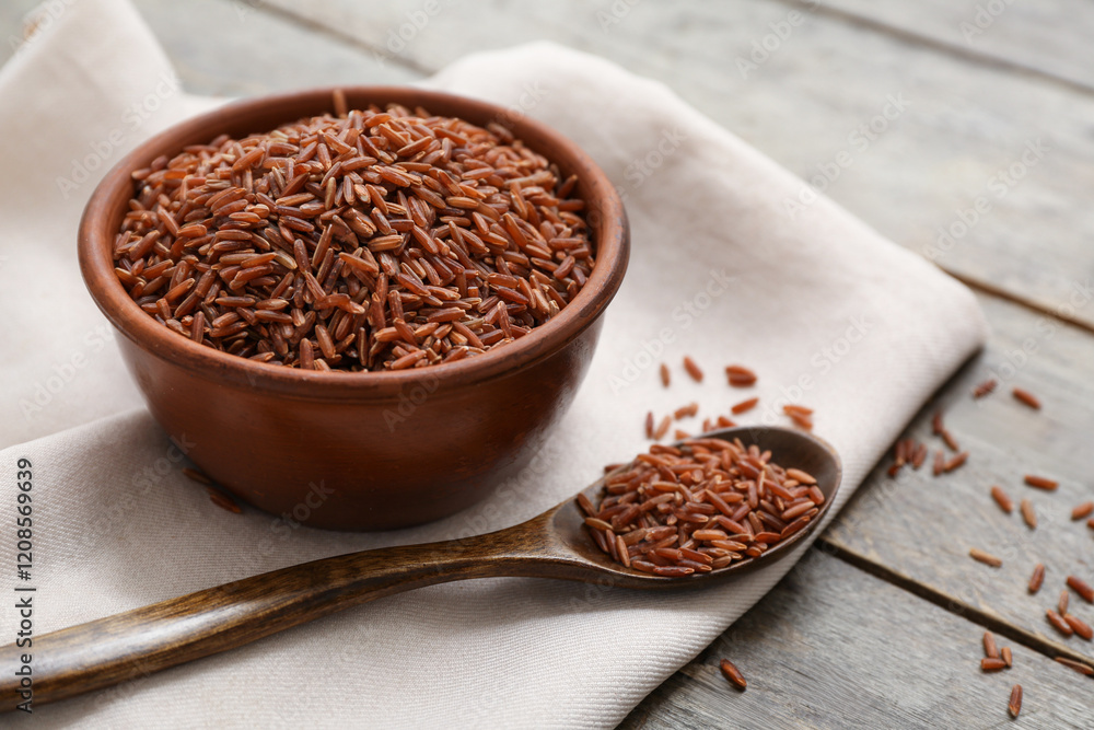 Bowl and spoon with raw brown rice on wooden background Bowl and spoon with raw brown rice on wooden background