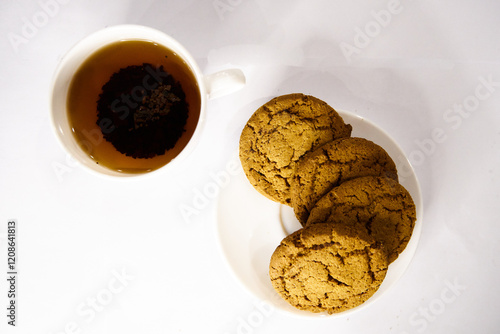 Oatmeal cookies on a white plate and a cup of black tea