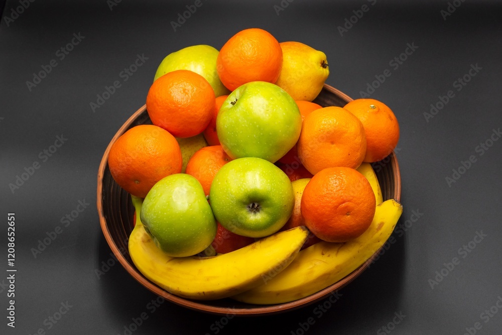 Fresh ripe fruits in a bowl on a gray background. Fruit mix of tangerines, pears, bananas, apples. Healthy eating. Vitamins. Fresh ripe fruits in a bowl on a gray background. Fruit mix of tangerines, pears, bananas, apples. Healthy eating. Vitamins.