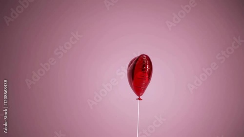 Red heart-shaped balloon with pink background, romantic celebration and love concept